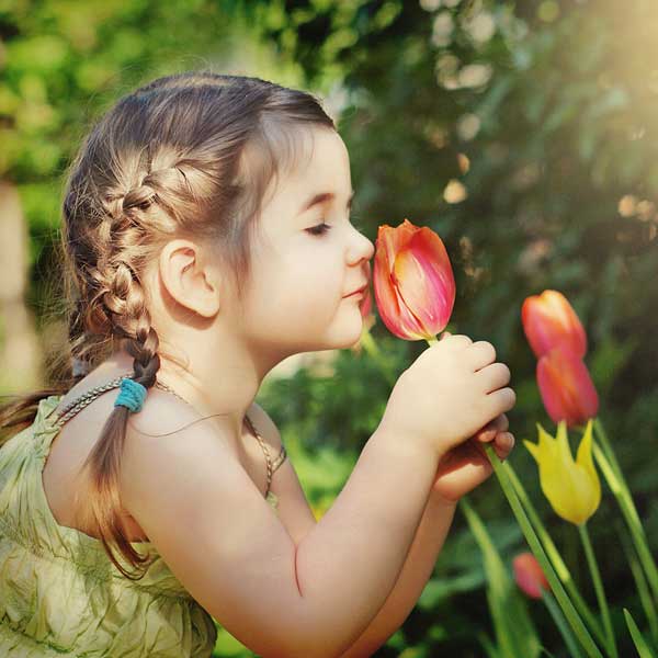 کودک در حال بوییدن گل لاله